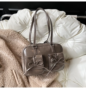 Detail of dark taupe glossy faux leather shoulder bag with decorative bow front pockets