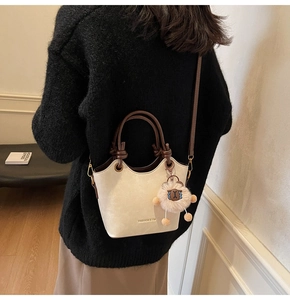 Detail of cream bucket bag with wavy edge, brown woven handle and cute sheep charm