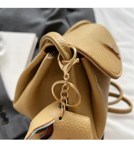 Macro view of gold metal hook and hardware on khaki litchi grain leather bag side