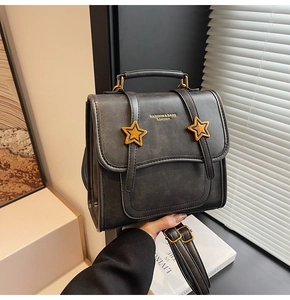 Close-up of vintage grey leather handbag featuring golden star buckles and handle