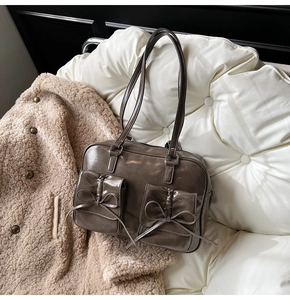 Close-up of vintage dark brown glossy leather bag with bow details and front pockets