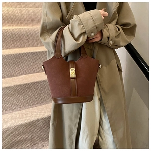 Brown frosted suede bucket bag detail with golden metal buckle and leather accents