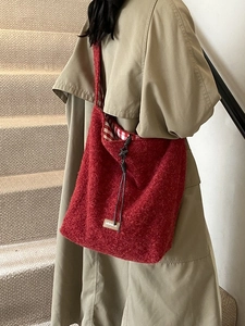 Sac fourre-tout rouge foncé en peluche porté par un mannequin en trench-coat