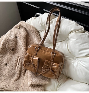 Close-up of caramel vintage leather shoulder bag with decorative bow pockets and shiny finish