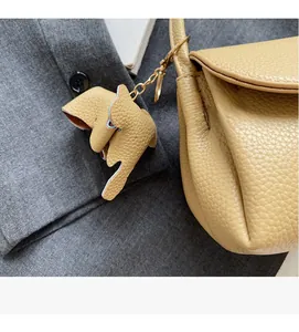 Detail of beige lychee grain leather handbag with gold hardware and elephant charm