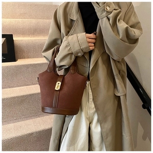 Detail of dark brown vintage bucket bag featuring suede and leather patchwork with gold buckle