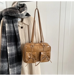 Detail of light brown faux leather handbag with decorative bows and glossy finish