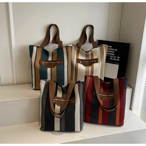 Detailed view of four textured striped canvas tote bags with signature metallic hardware
