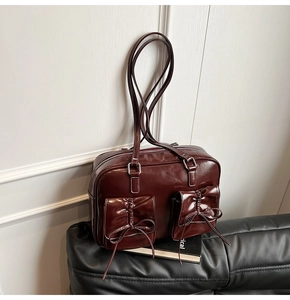 Close-up of a vintage dark red glossy faux leather Boston bag with ribbon bow details