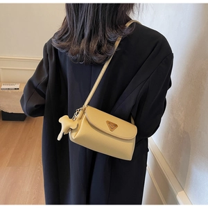Detailed macro view of cream leather cross-body bag with cute elephant charm accessory