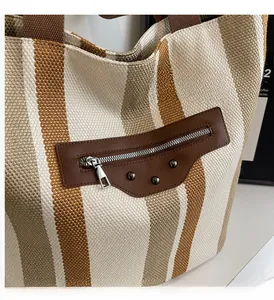 Macro shot of striped canvas tote with leather hardware and vintage metal rivet details