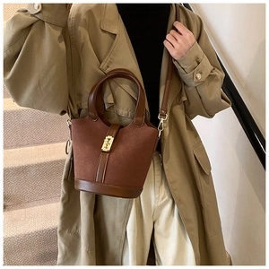 Close-up of vintage brown suede bucket bag with smooth leather trim and gold hardware