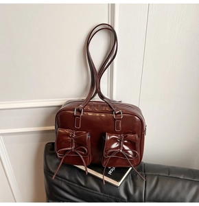 Close-up of vintage dark brown faux leather bag with bow pockets on a black leather seat