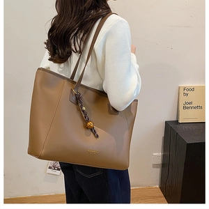 Dettaglio della borsa tote marrone con stampa dorata e ciondolo di perline intrecciate
