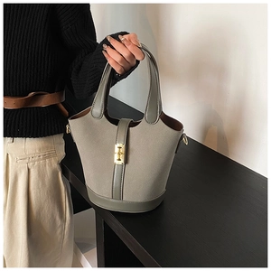 Detailed view of sage green bucket bag with matte texture and gold metal latch