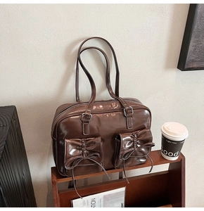 Detail of dark brown glossy patent leather shoulder bag with bow-knot flap pockets