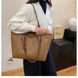 Dettaglio di una grande borsa tote in ecopelle marrone con scritta Fashion & Bags su modella