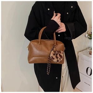 Détail d'un sac boston en cuir marron avec breloque cœur léopard et garnitures dorées