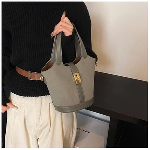 Detail of dark olive bucket bag featuring suede texture and gold twist-lock closure