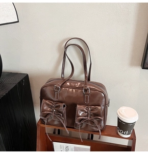Detail of vintage brown leather bag with bow-knot pockets on a wooden stand