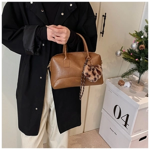 Détail d'un sac oreiller en cuir marron vintage avec pendentif cœur léopard