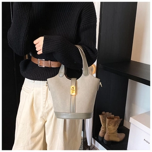 Detail of sage green bucket bag with gold metal buckle and smooth leather texture
