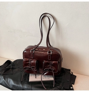 Close-up of vintage dark brown glossy leather bag with bow-decorated front flap pockets