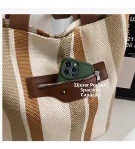 Detail of canvas tote bag showing striped texture and leather front pocket with phone