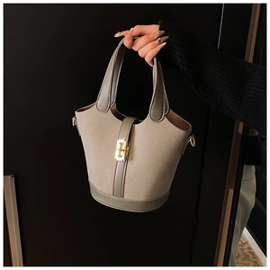 Detail view of khaki suede bucket bag with olive green handles and golden metal buckle