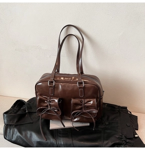 Close-up of vintage brown patent leather bag featuring bow details and contrast stitching