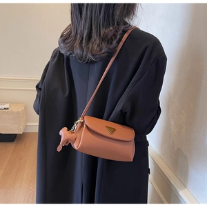 Detail of brown litchi pattern leather crossbody bag with vintage gold triangular clasp