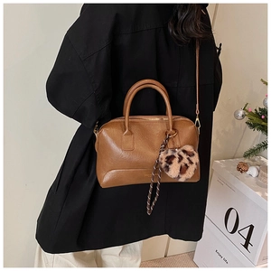 Détail du sac polochon rétro marron avec pompon léopard et lettrage doré élégant