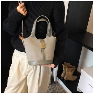 Chic grey bucket bag with golden lock shown on model with shoulder strap and dual handles