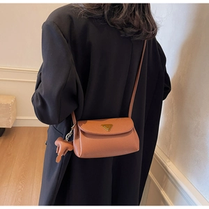 Detailed view of brown leather square bag with gold metal buckle and cute elephant charm