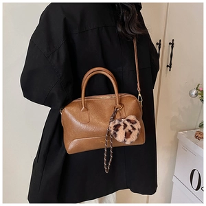 Sac oreiller vintage marron avec breloque cœur léopard et bandoulière porté par un mannequin