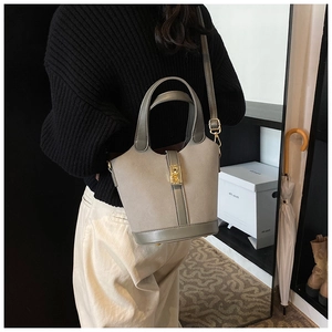 Detailed side view of a sage green bucket bag with gold hardware and shoulder strap