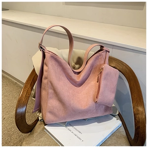 Pink suede tote bag with matching zippered pouch on a light wood chair detail