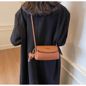 Close-up of brown litchi textured leather crossbody bag with cute elephant charm