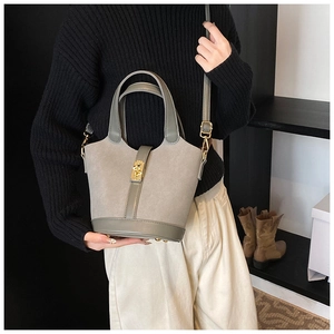 Detail of taupe bucket bag showing mixed suede texture and gold twist-lock closure