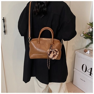 Détail d'un sac à main en cuir marron avec charme cœur léopard sur une boîte décor