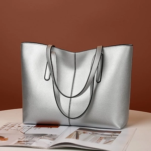 Primer plano de un bolso tote plateado metalizado con acabado brillante y costura central