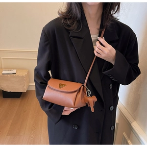 Close-up of brown pebble leather crossbody bag with vintage gold metal and elephant charm