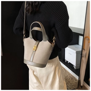 Detail of grey suede bucket bag with gold lock and detachable strap on model