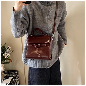 Nahaufnahme einer rotbraunen Vintage-Handtasche mit Schnallendetails und Lederstruktur