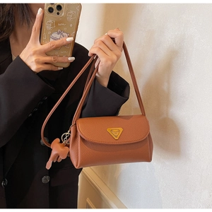 Close-up of brown litchi pattern leather bag with gold hardware and elephant charm