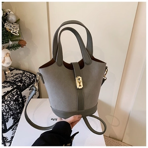 Detail view of grey-green bucket bag featuring gold metal buckle and matte leather texture