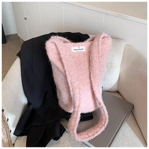 Détail du sac fourre-tout rose pelucheux avec étiquette 'have a nice day' sur tricot
