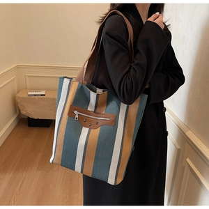 Detail of canvas tote bag featuring vertical stripes and vintage rivet leather patch