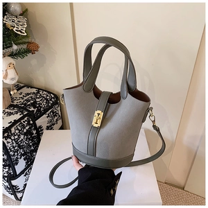 Detail of grey suede and leather bucket bag with gold T-clasp on festive white platform