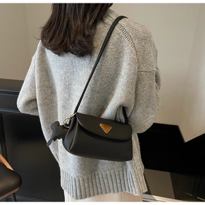 Detail of black lychee grain leather shoulder bag with golden triangle logo and dog charm